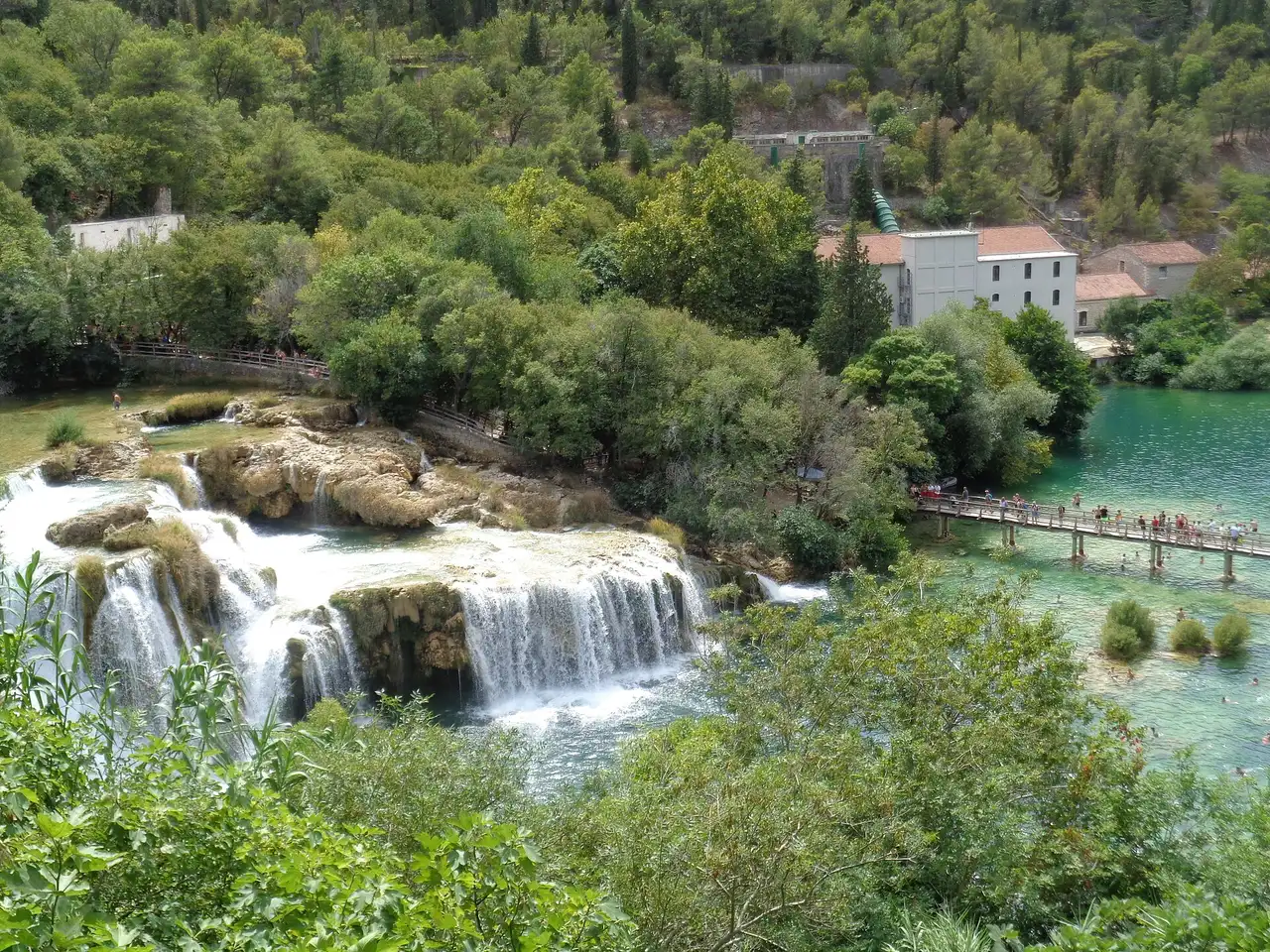 Wooden boardwalks over green water and tufa barriers, the shared landscape of the Plitvice or Krka decision