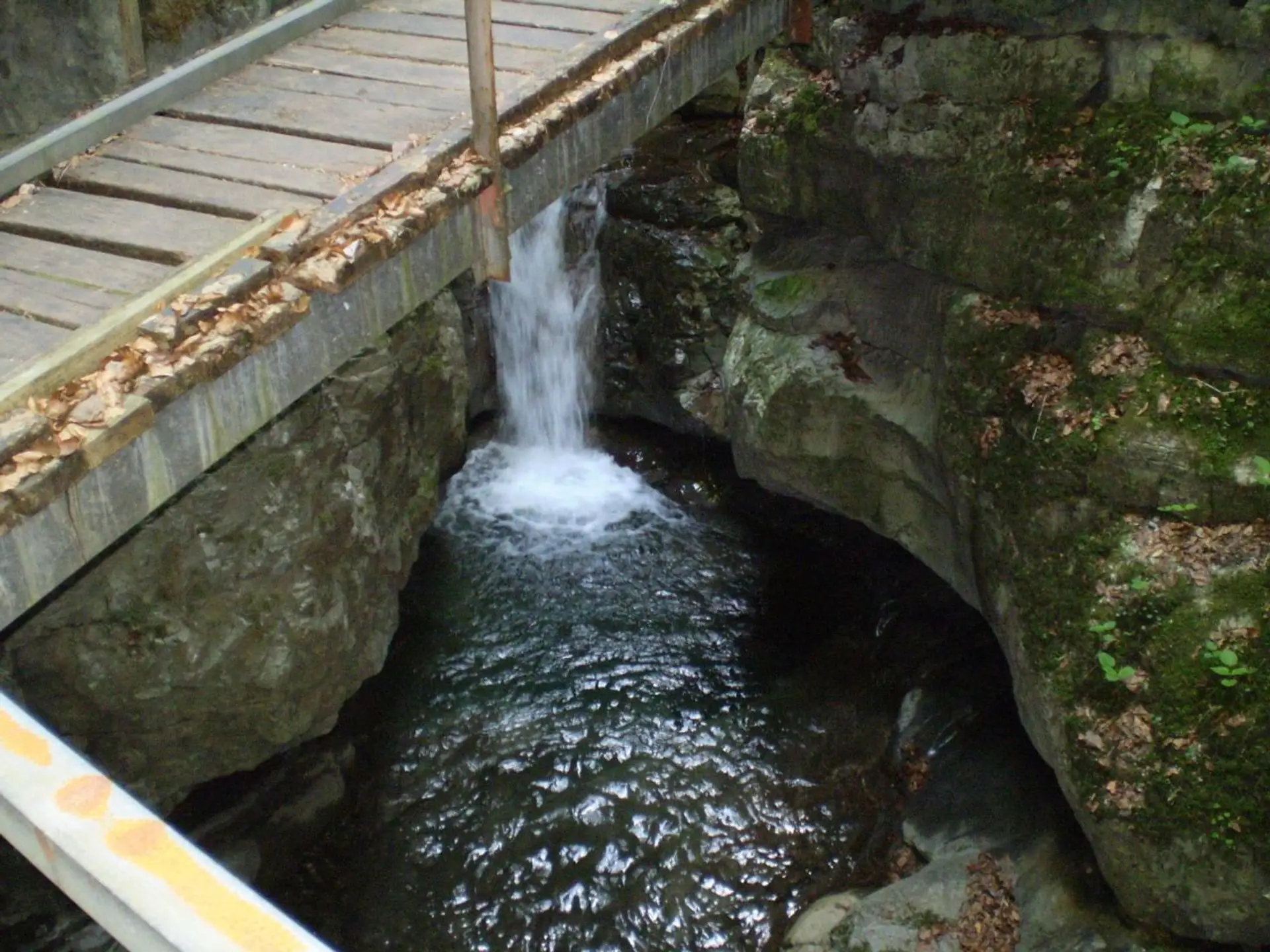 The fenced wooden walkway of Vražji prolaz crossing the narrow Jasle canyon over wet limestone slabs