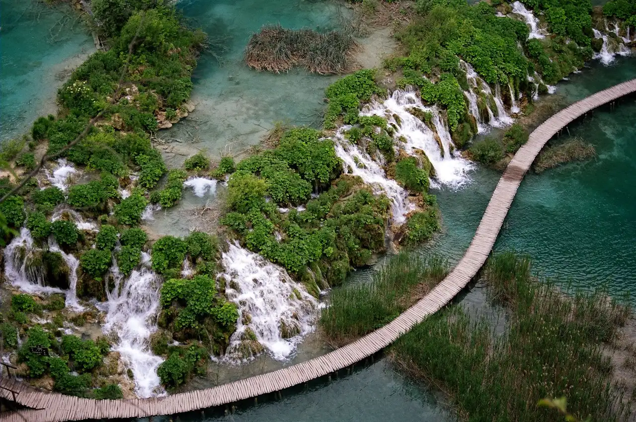 A family on the fenced boardwalks above green basins — croatia waterfalls with kids graded site by site